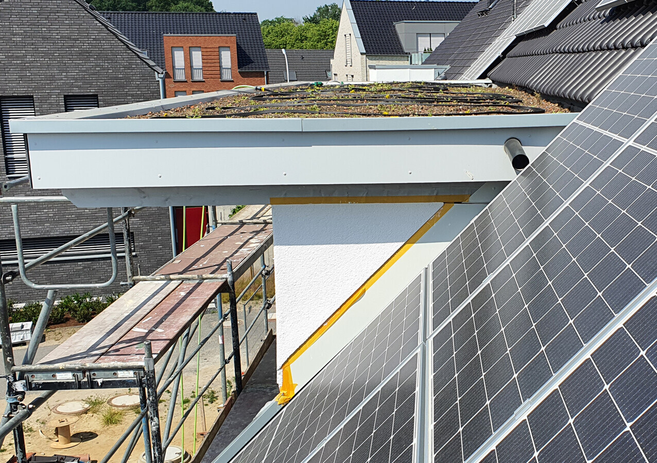 Top view: roof with solar panels, scaffolding, and green flat roof section.