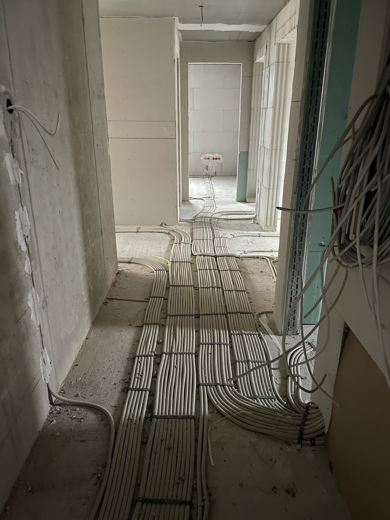 Hallway in shell construction with installed cable ducts and open electrical installation