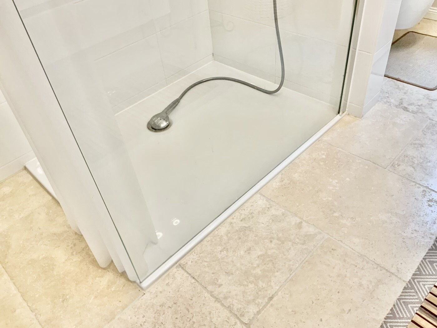 Shower enclosure with glass panel, handheld showerhead on flexible hose in the shower tray.