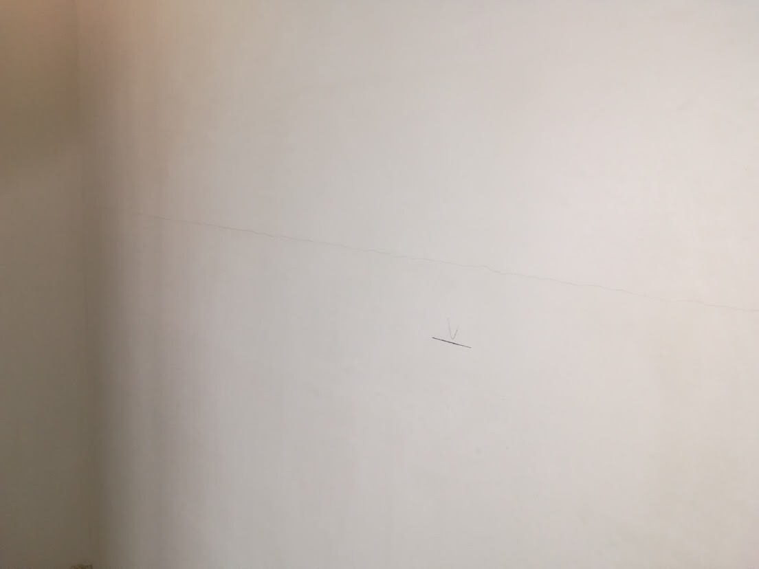 Beige wall with a fine horizontal crack line and a small marking line.