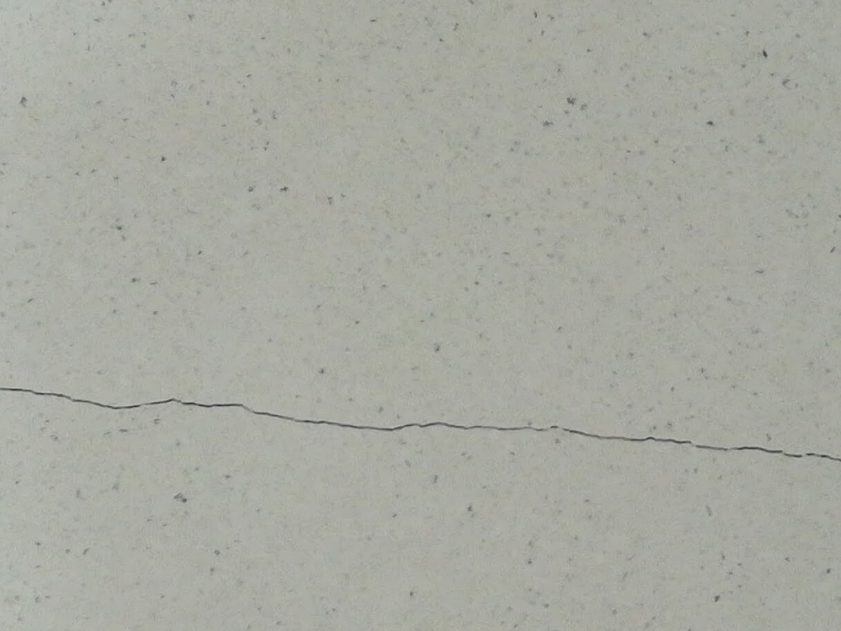 Light gray concrete wall with a fine speckled texture and a horizontal crack line.