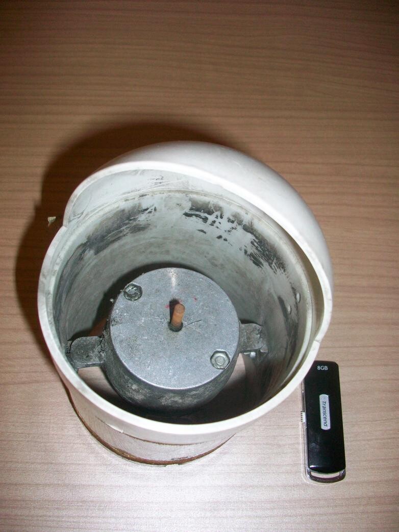 White ceiling lamp base with metal motor inside, lying on a wooden surface.