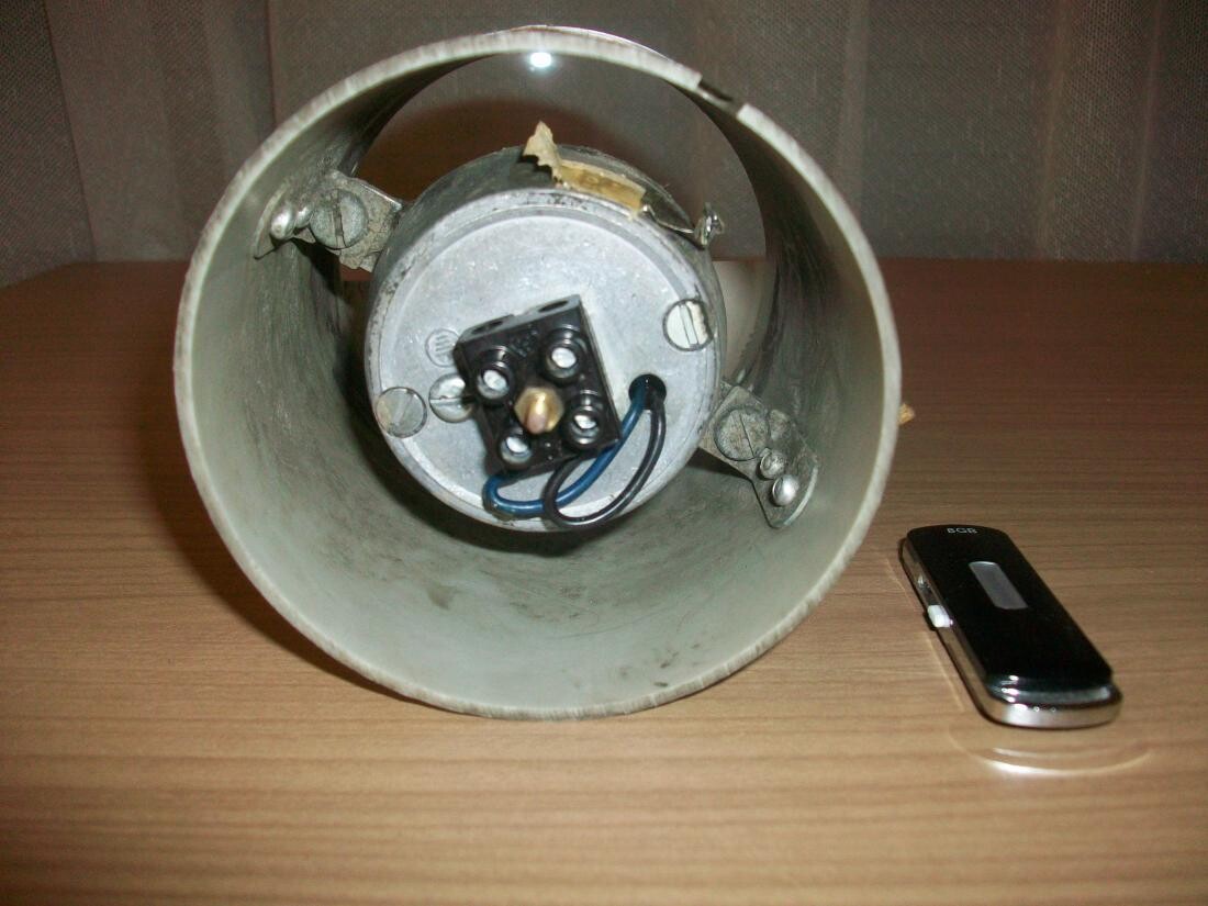 Metal ceiling lamp with wire connections lying on a wooden table.