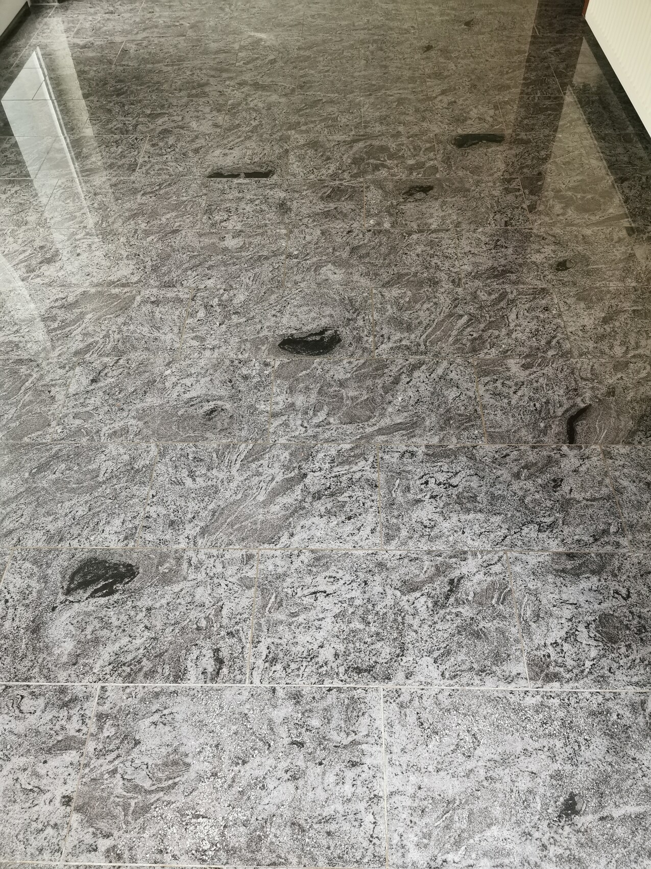 Grey marble-effect tile floor with dark spots and glossy reflections.