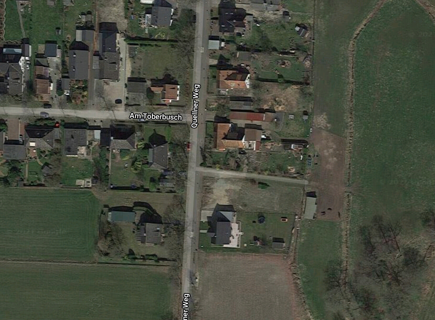Aerial photo of a village district; Am Toberbusch intersects Quelliner Weg, houses and gardens.