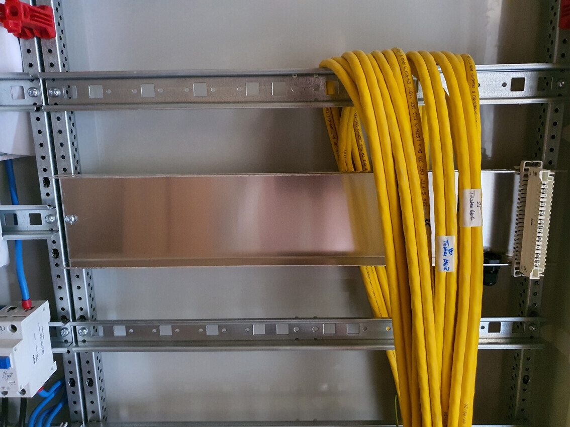 Yellow network cable bundle hanging on a metal rack in the server cabinet; blue cables next to it.