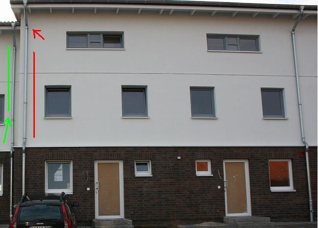 Exterior view of a two-story residential building with gray facade, brown doors and windows
