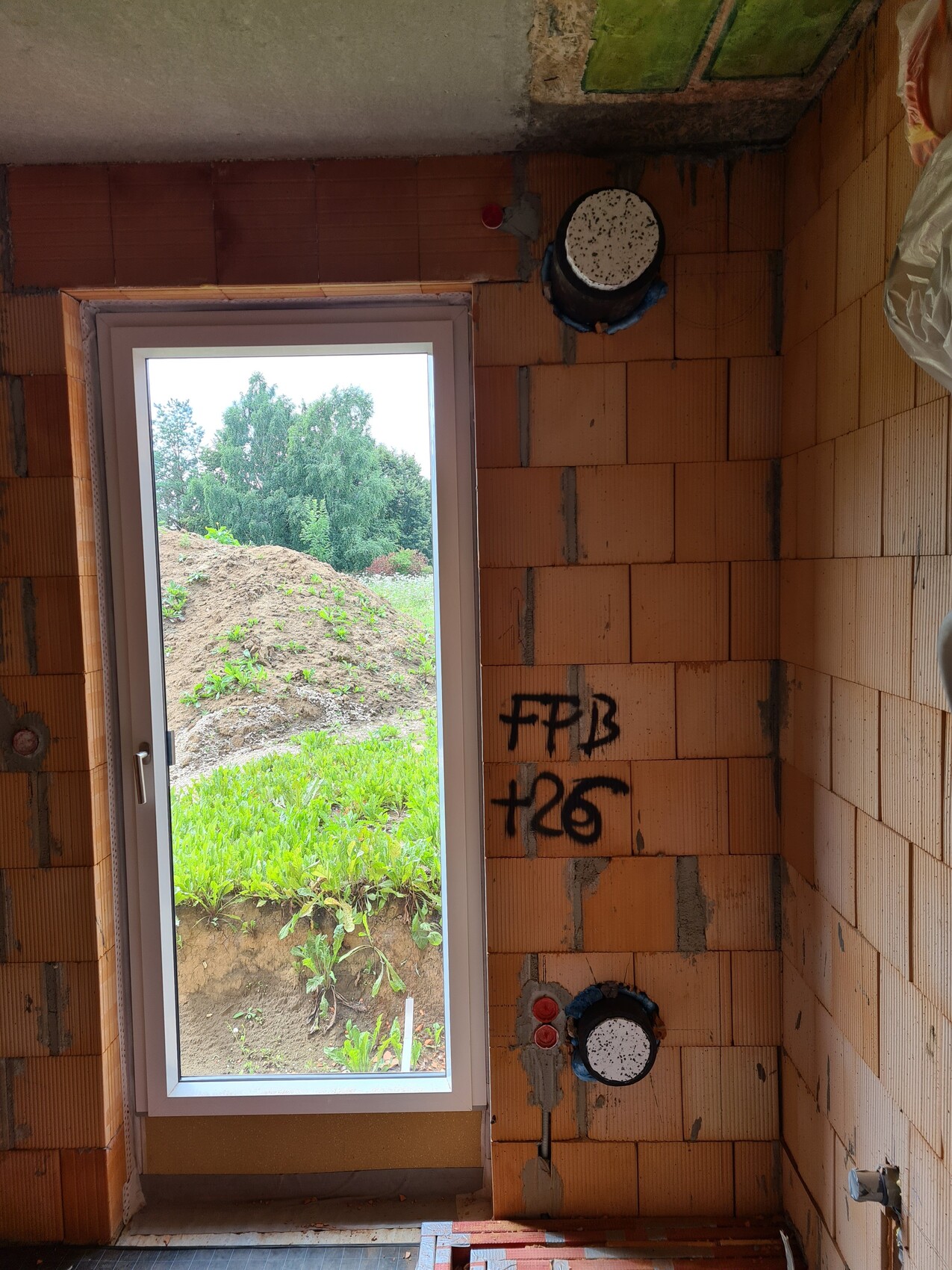 Unfinished bathroom shell with wall blocks, installations, and window view