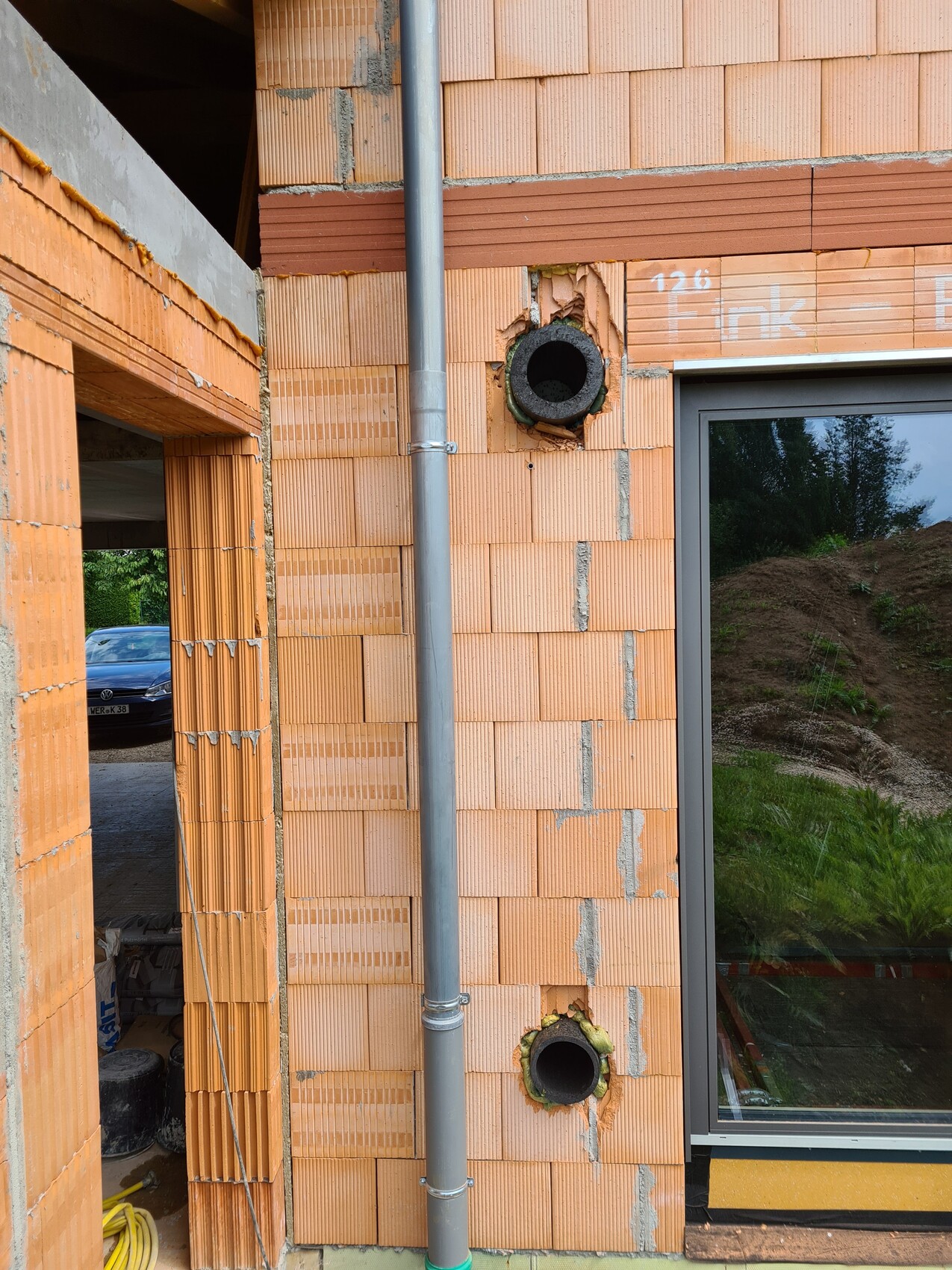 Exterior brick wall with piping and circular opening at construction site