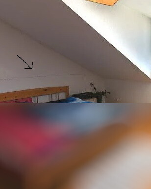 Bedroom in the attic with sloped ceiling and wooden bed
