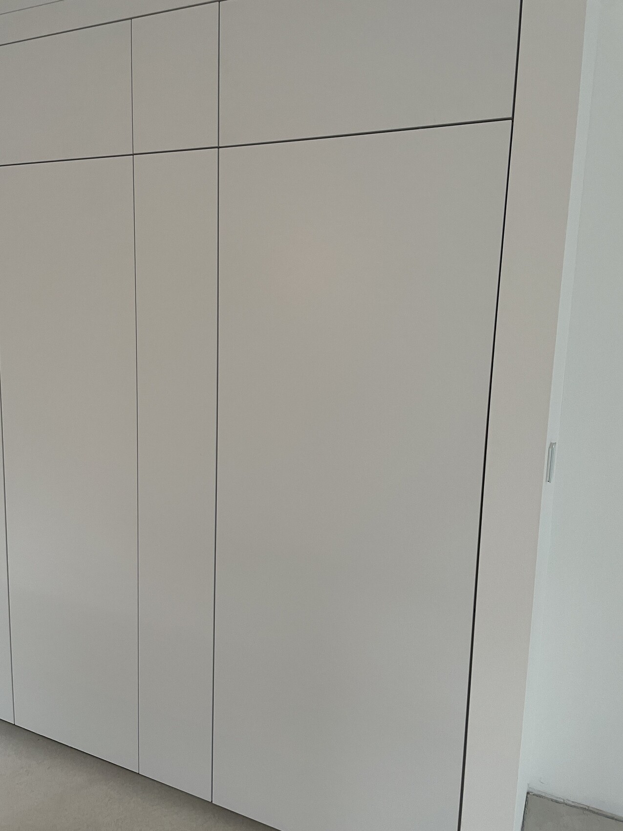 White modern wardrobe with smooth fronts and vertical grooves.