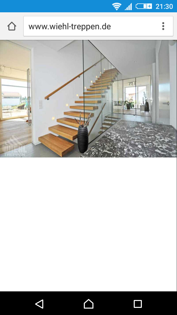 Moderne Treppe mit Holzstufen und Glasgeländer im hellen Innenbereich eines Hauses