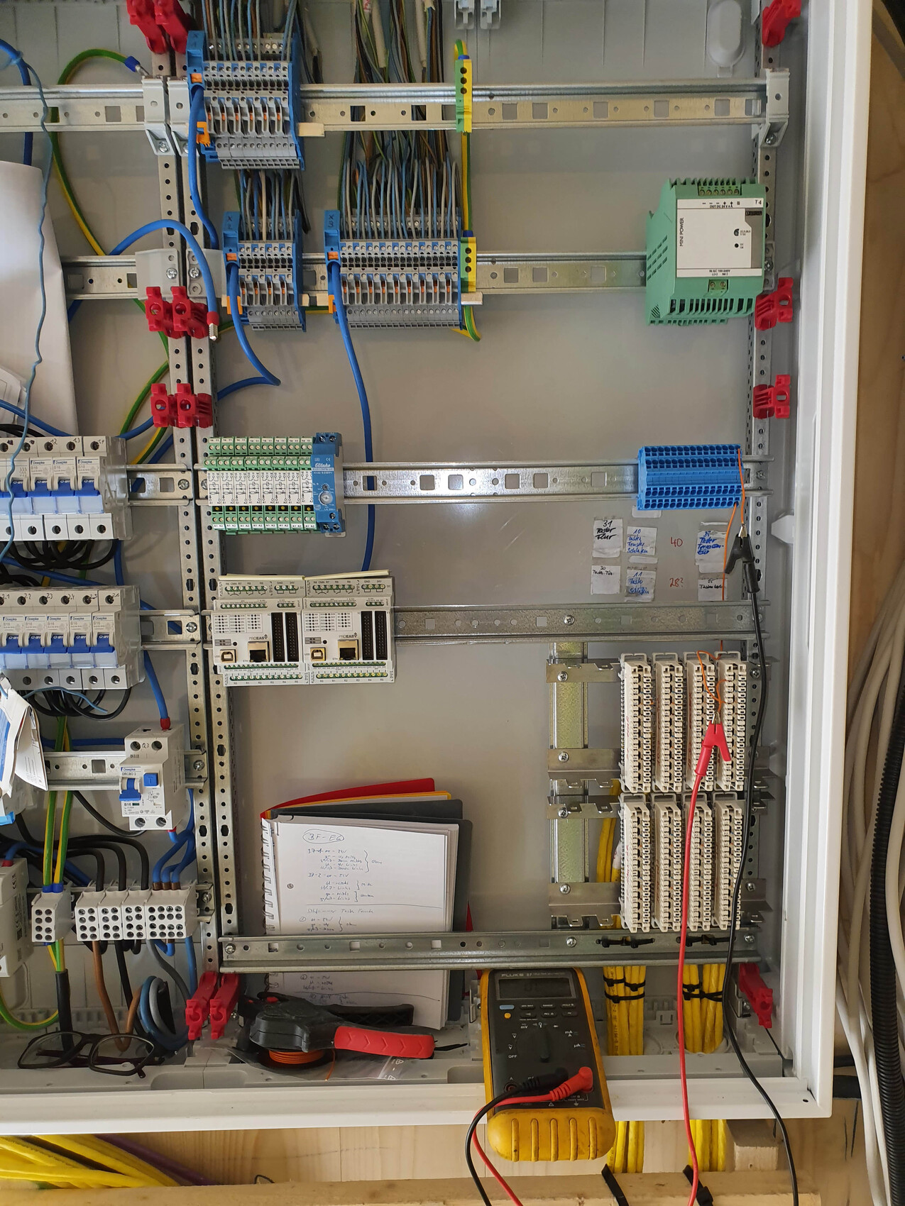 Control cabinet with wiring, terminal strips, relays, multimeter and tools.