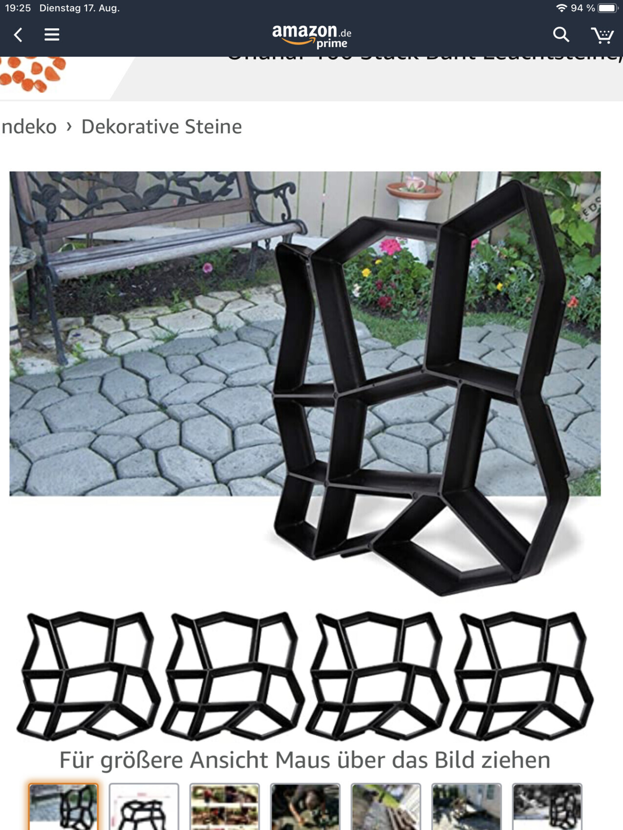 Black geometric sculpture made of connected polygon frames on a paved garden forecourt.