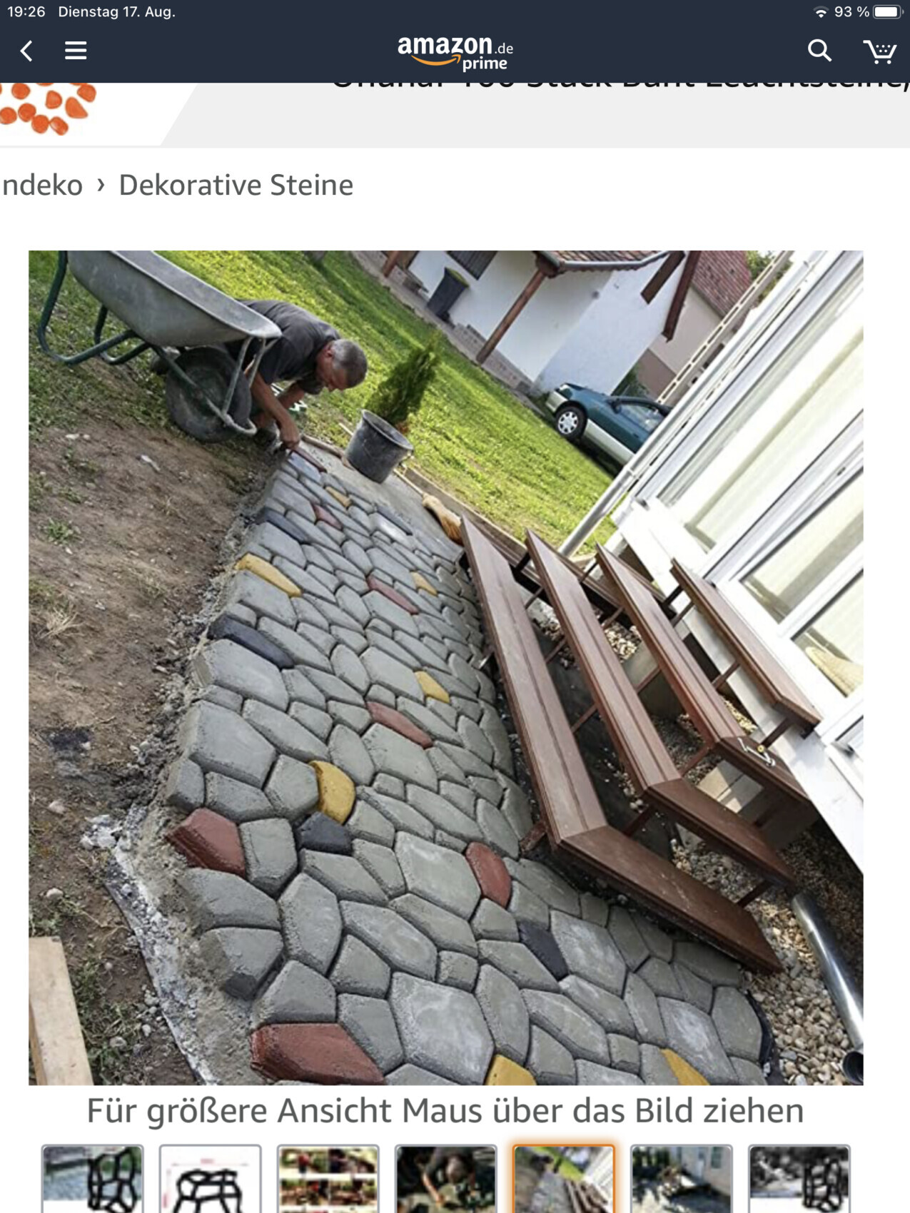 Man laying colorful stone paving next to the house, wooden stairs are ready.