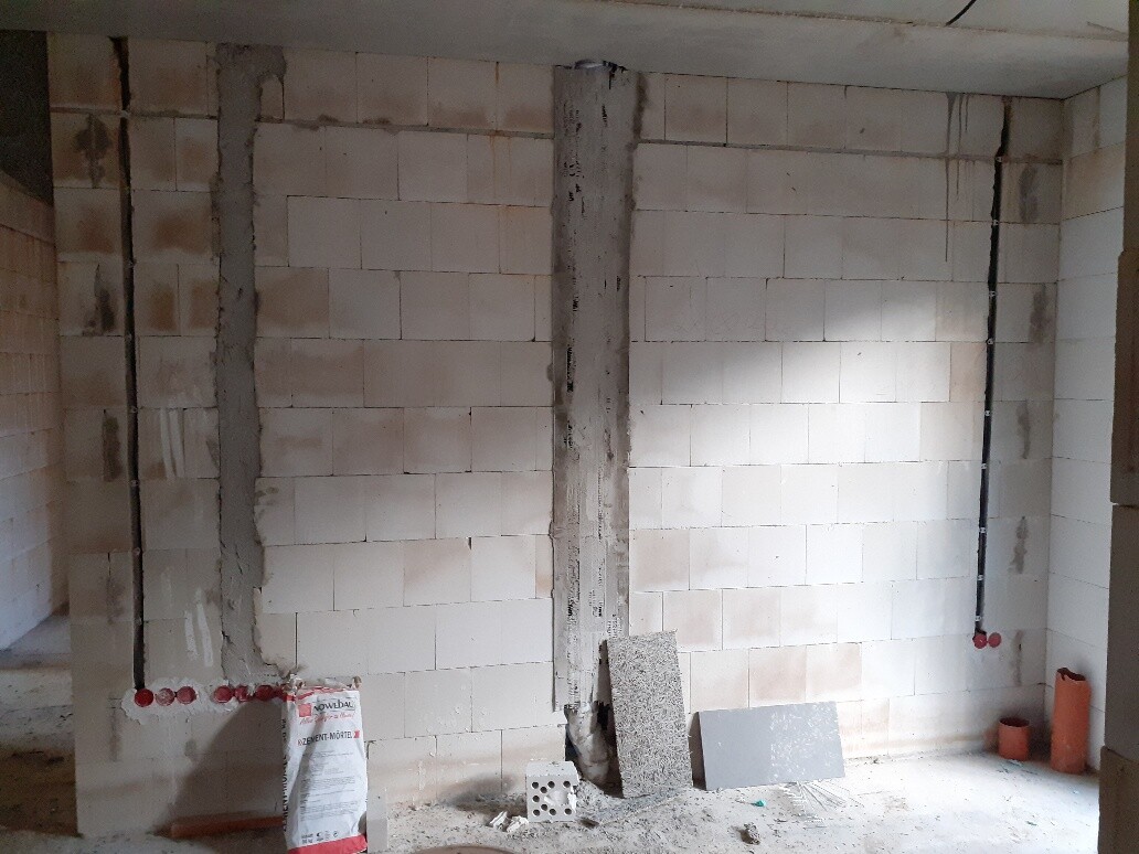 Unfinished interior with concrete support, wall blocks, piping, and building materials.