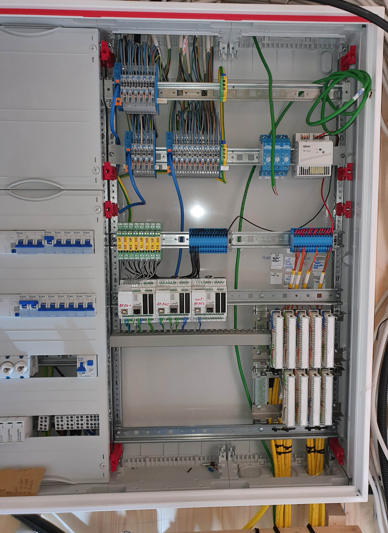 Open control cabinet with wiring, terminals, relays, fuses, and busbars.