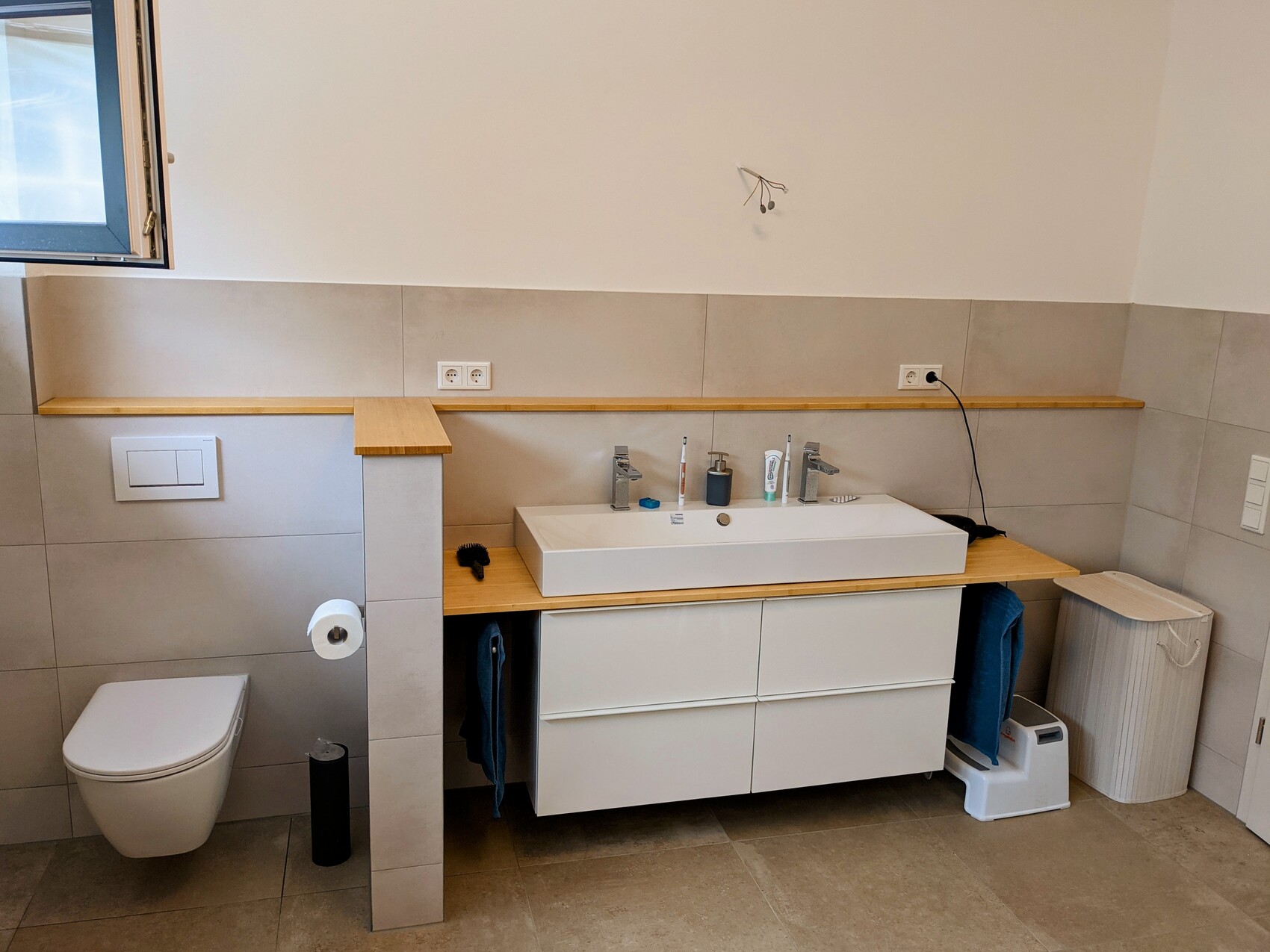 Badezimmer mit wandhängendem WC, Waschbecken auf Holzkonsole, Schubladenunterschrank