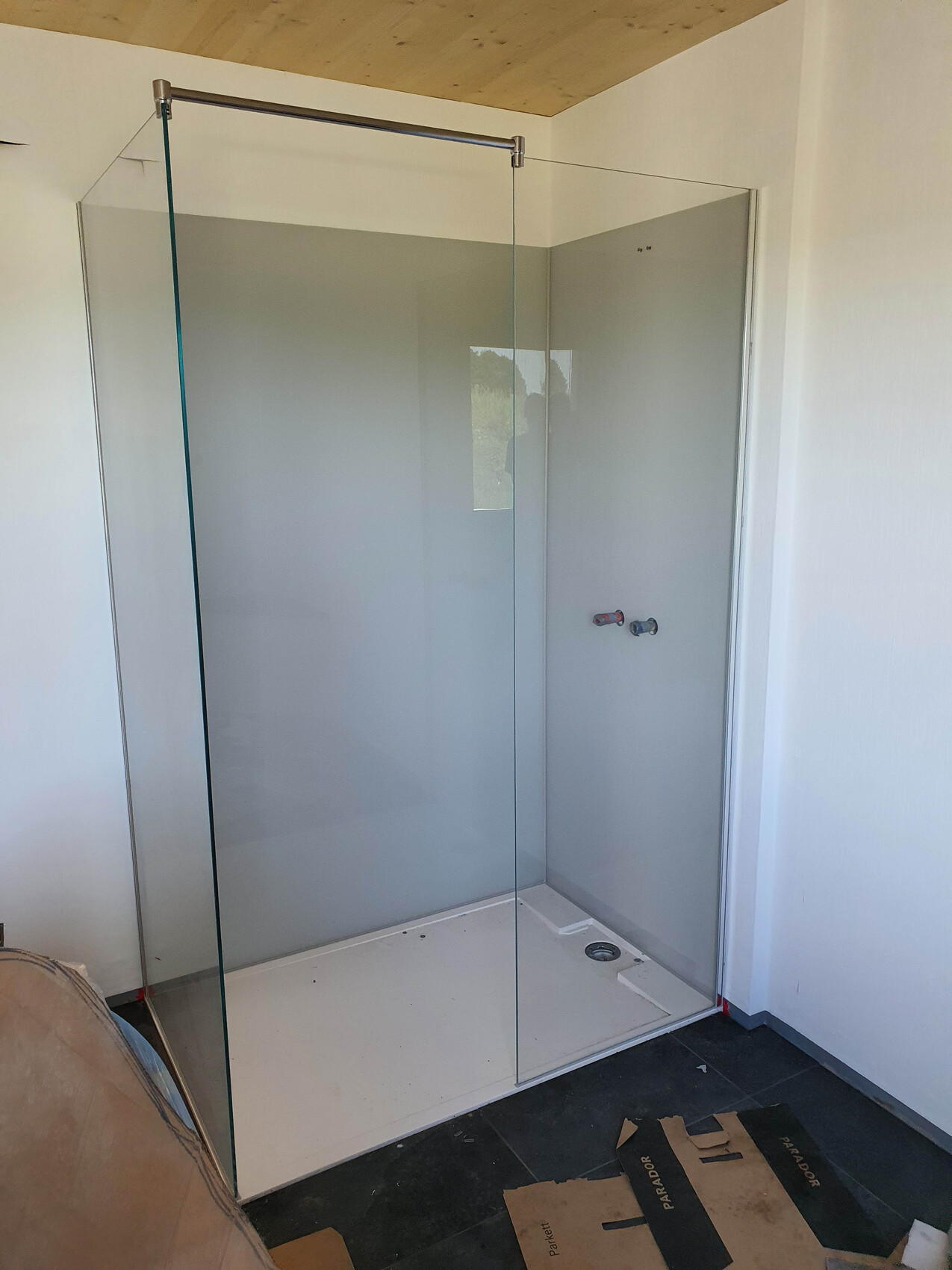 Shower enclosure made of glass in the construction phase, corner entrance, white shower tray.