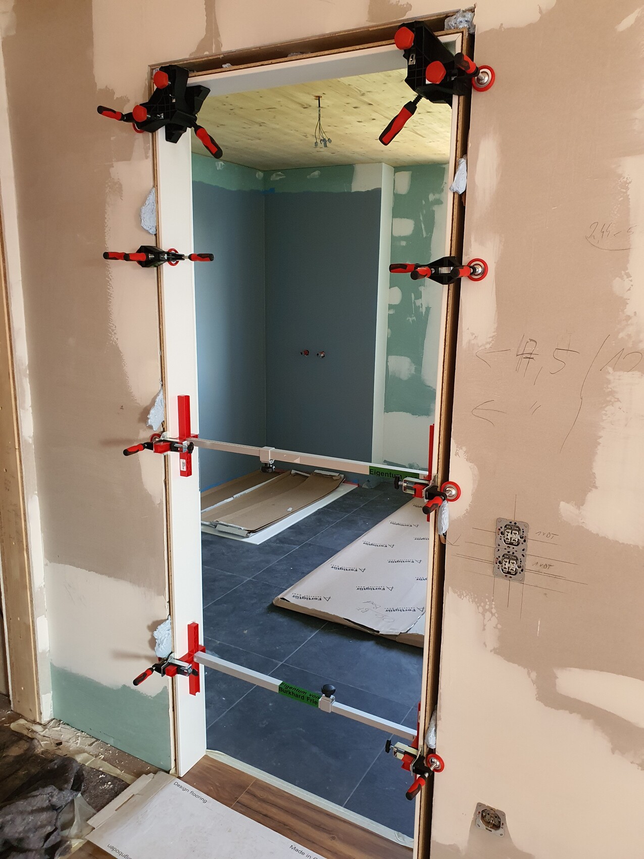 Door frame being fixed with clamps during interior construction, construction work in the adjacent room