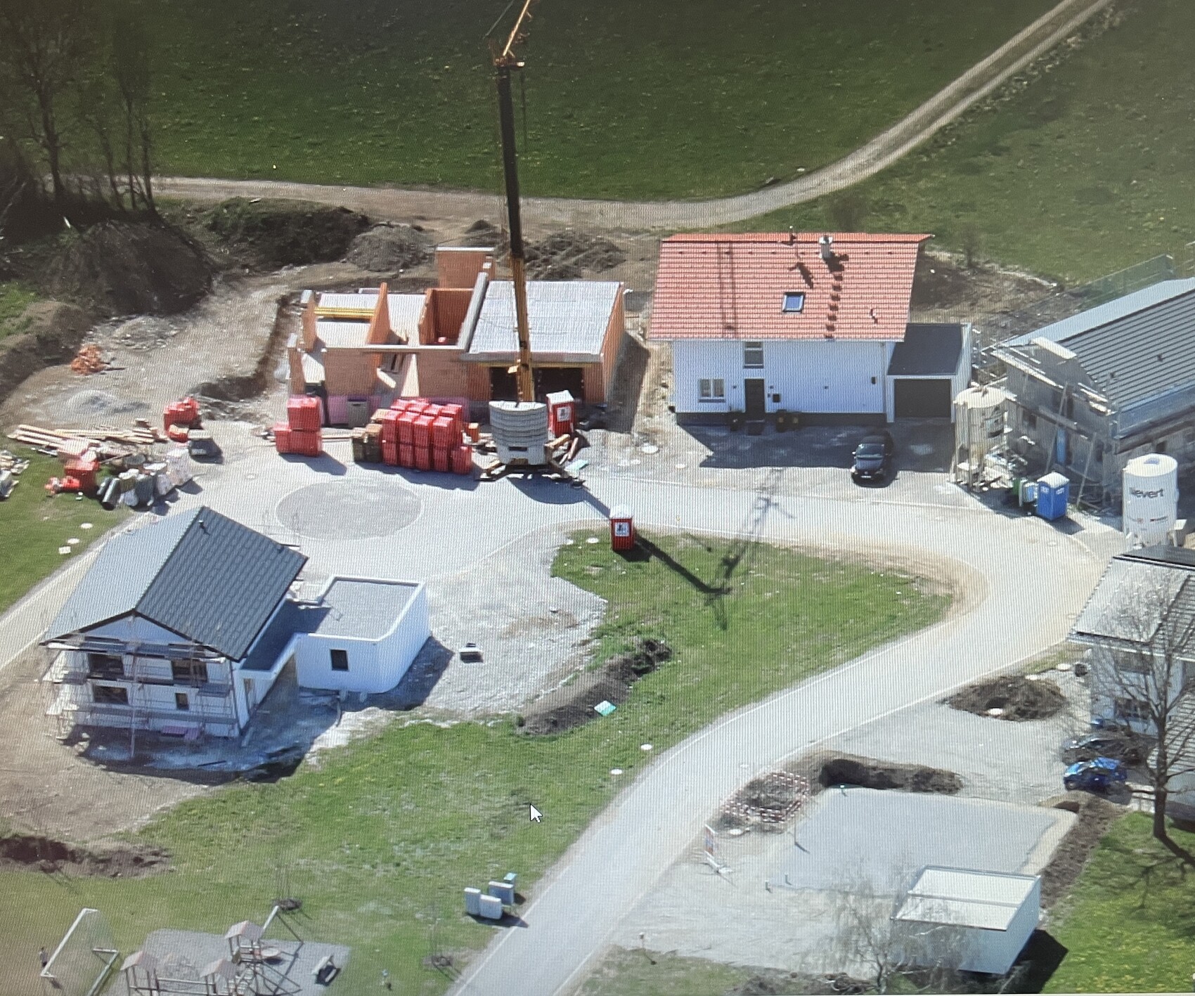 Aerial shot of a construction site with shell construction, foundation work, crane, and building materials