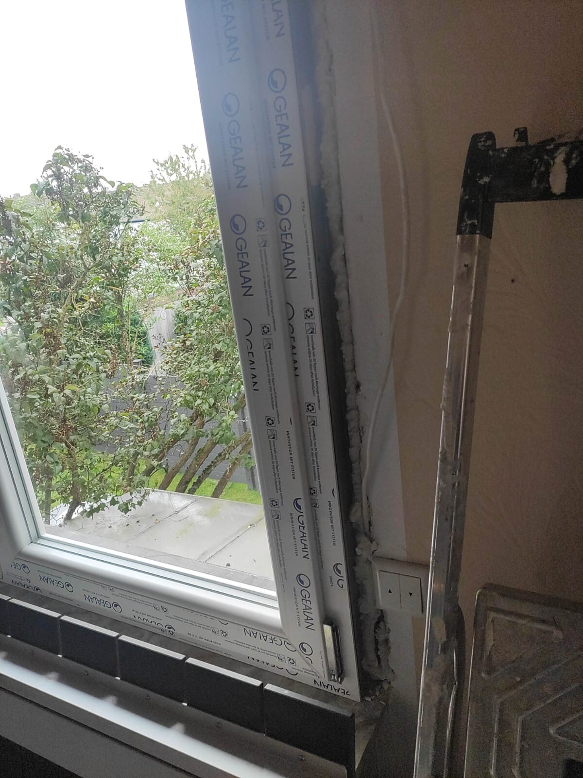 Interior: window installation with protective wrapping on the frame, view outside to trees