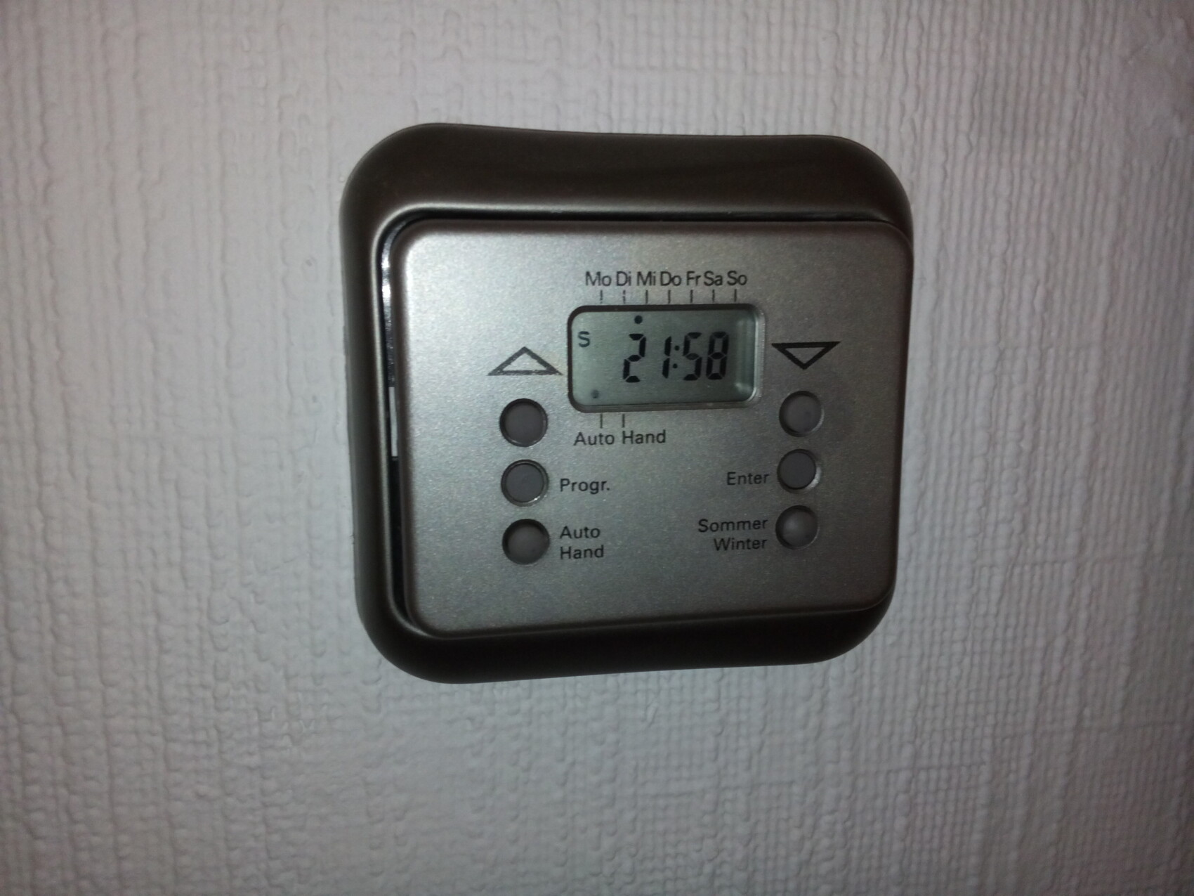 Digital wall thermostat with display and buttons on a light wall