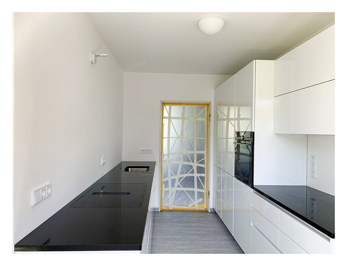 Modern kitchen with white cabinets, black countertop, and built-in oven.