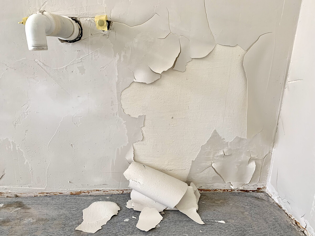 Interior wall with peeling plaster and plaster chunks on the floor
