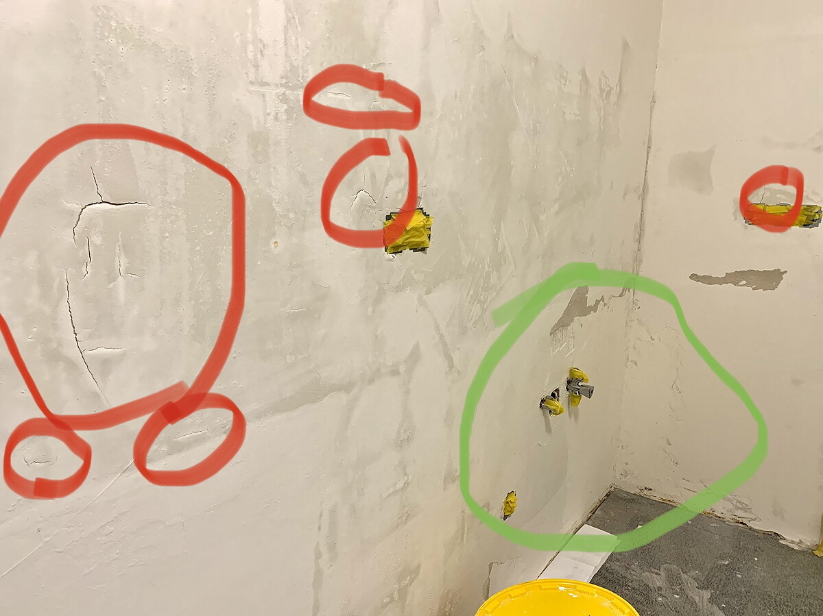 Bathroom wall with cracks and exposed water connections during construction work.