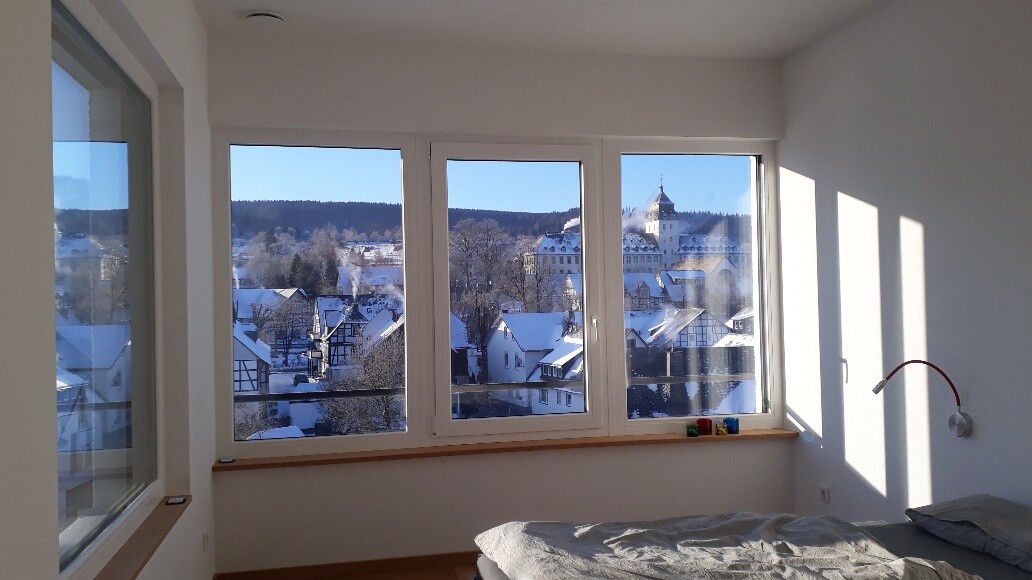 Bright bedroom with large windows and snowy city view