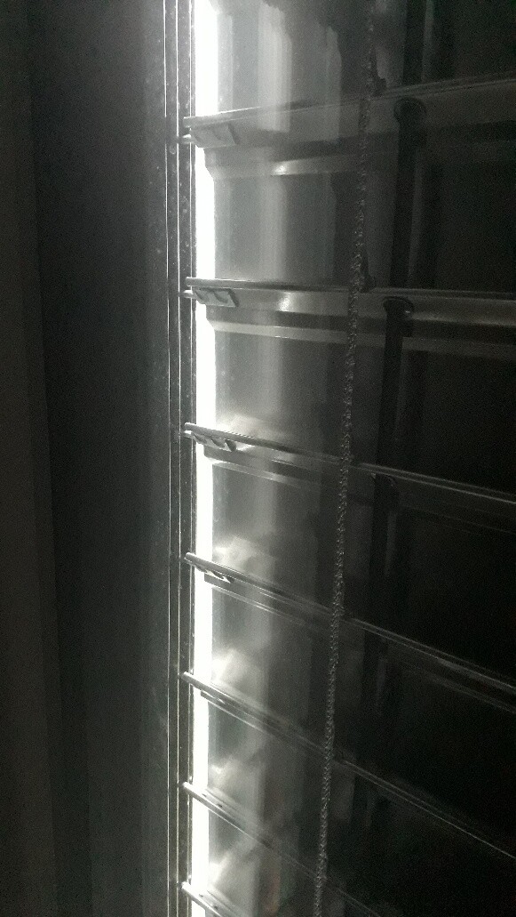 Horizontal slat blind with cord operation, light streaming through the slats.