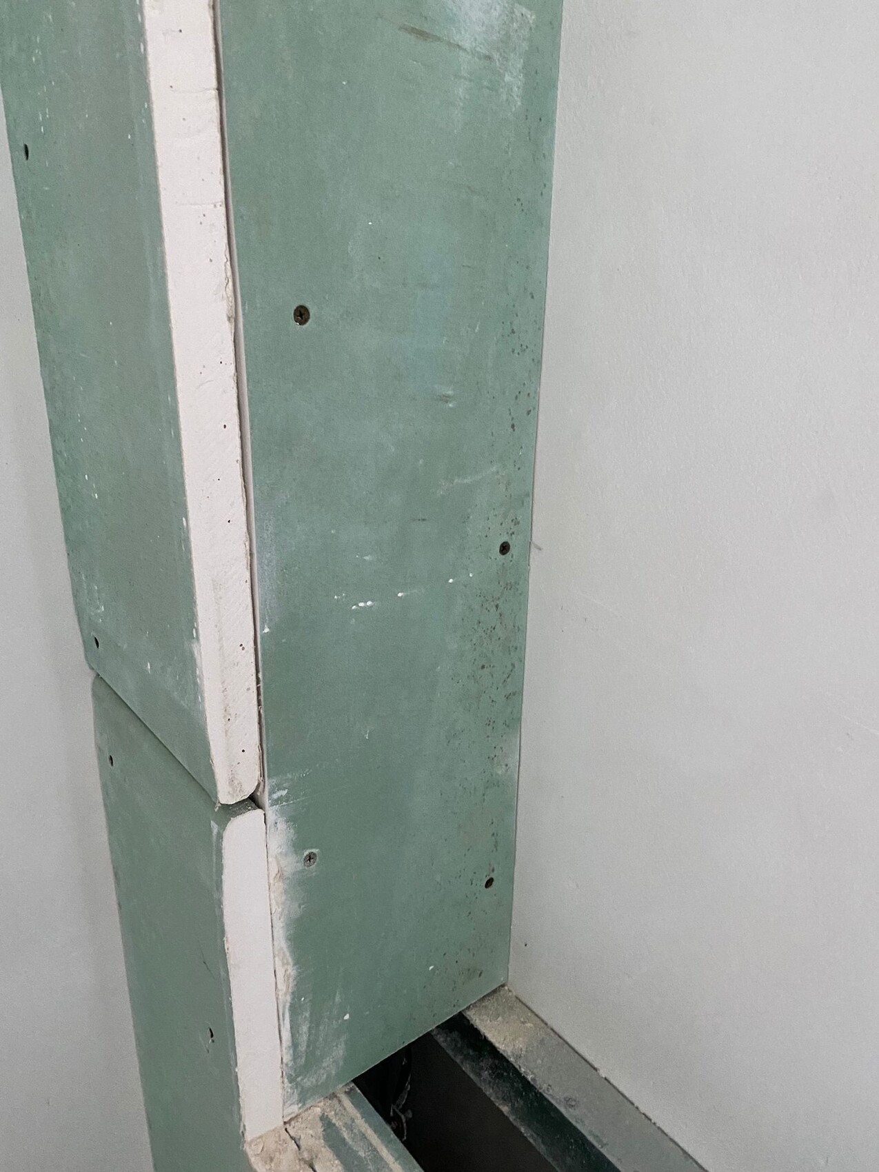 Close-up of green-painted door frame with white border, screws visible.