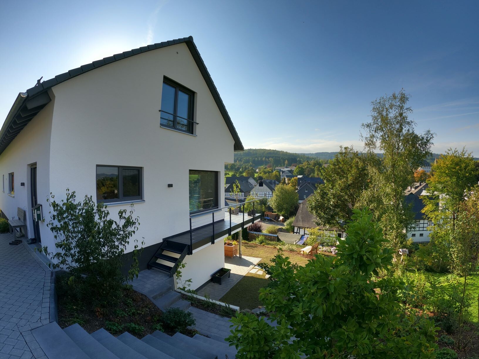 Modern white house with terrace and garden, looking out over gentle houses and landscape