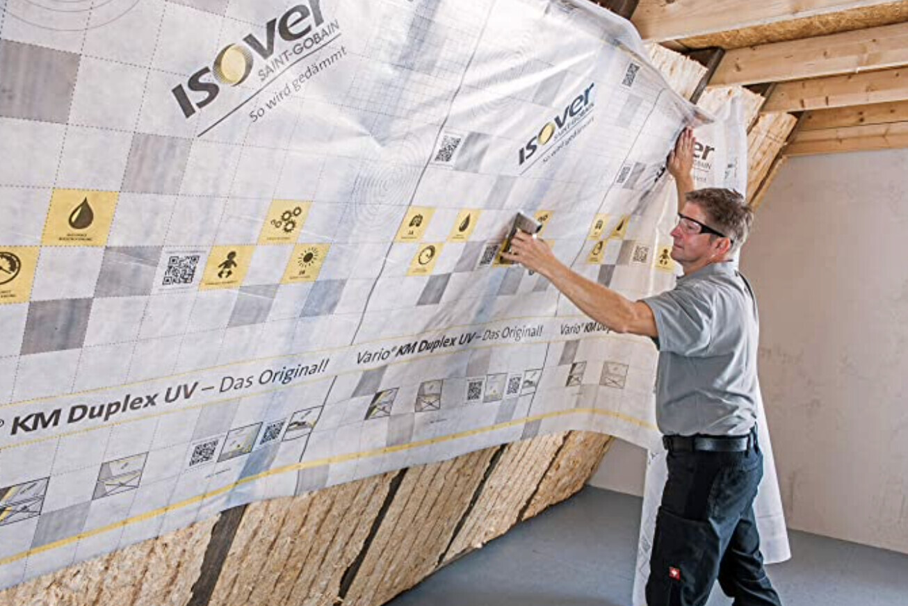 Fachkraft montiert Isover Dämmplatten an einer Wand eines Bauprojekts