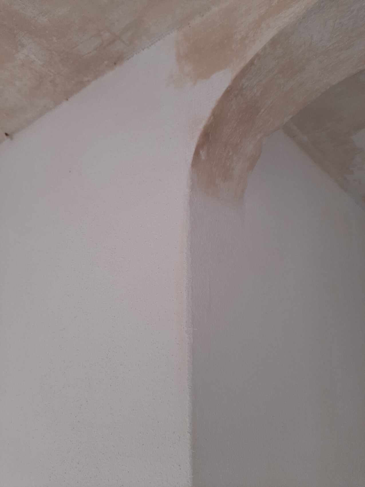 Roter Steinbogen über einer weiß verputzten Innenwand in einem Renovierungsraum.