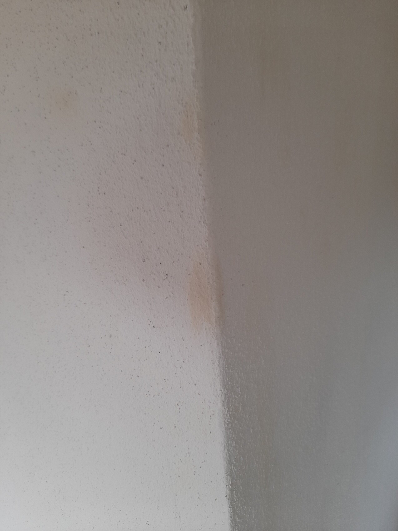 Innenwand-Ecke mit grober Putzstruktur, linke Seite hell, rechte Seite dunkler.