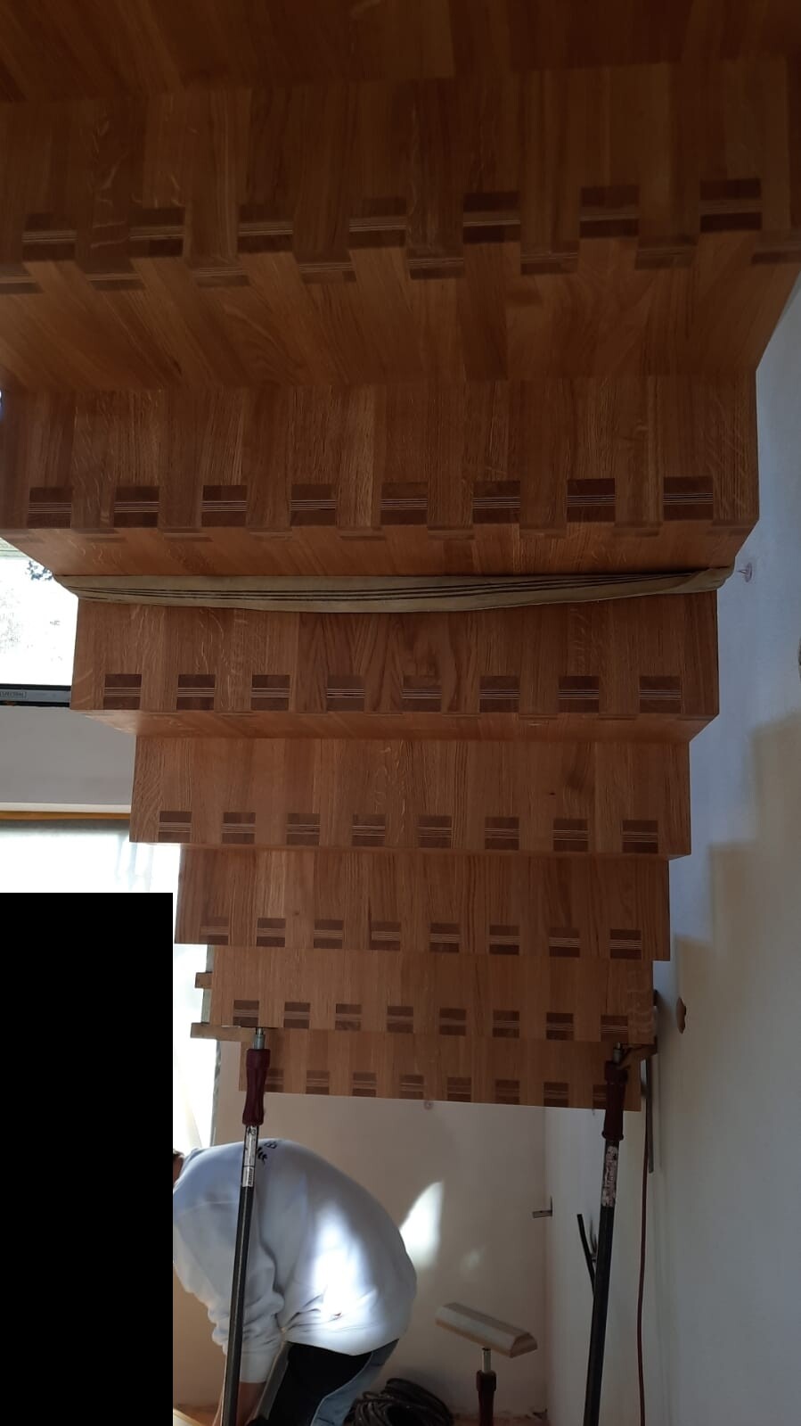 Wooden staircase under construction; steps with cut-outs, worker busy below.