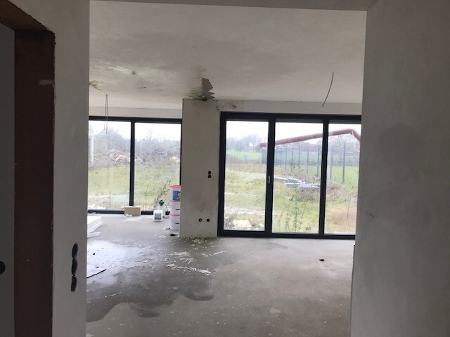 New build living space under construction with large glass doors and open windows.