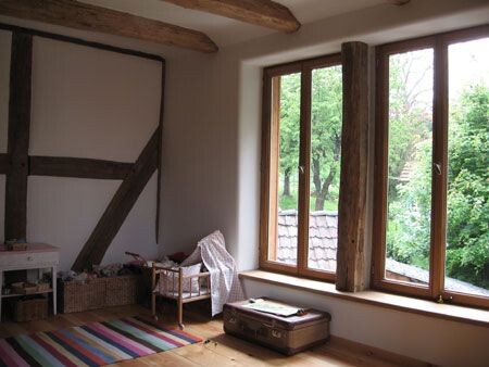 Interior with visible wooden beams, large window, and furniture during renovation