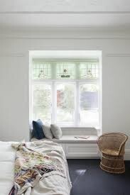 Bright bedroom with bed, window ledge seat, and wicker armchair