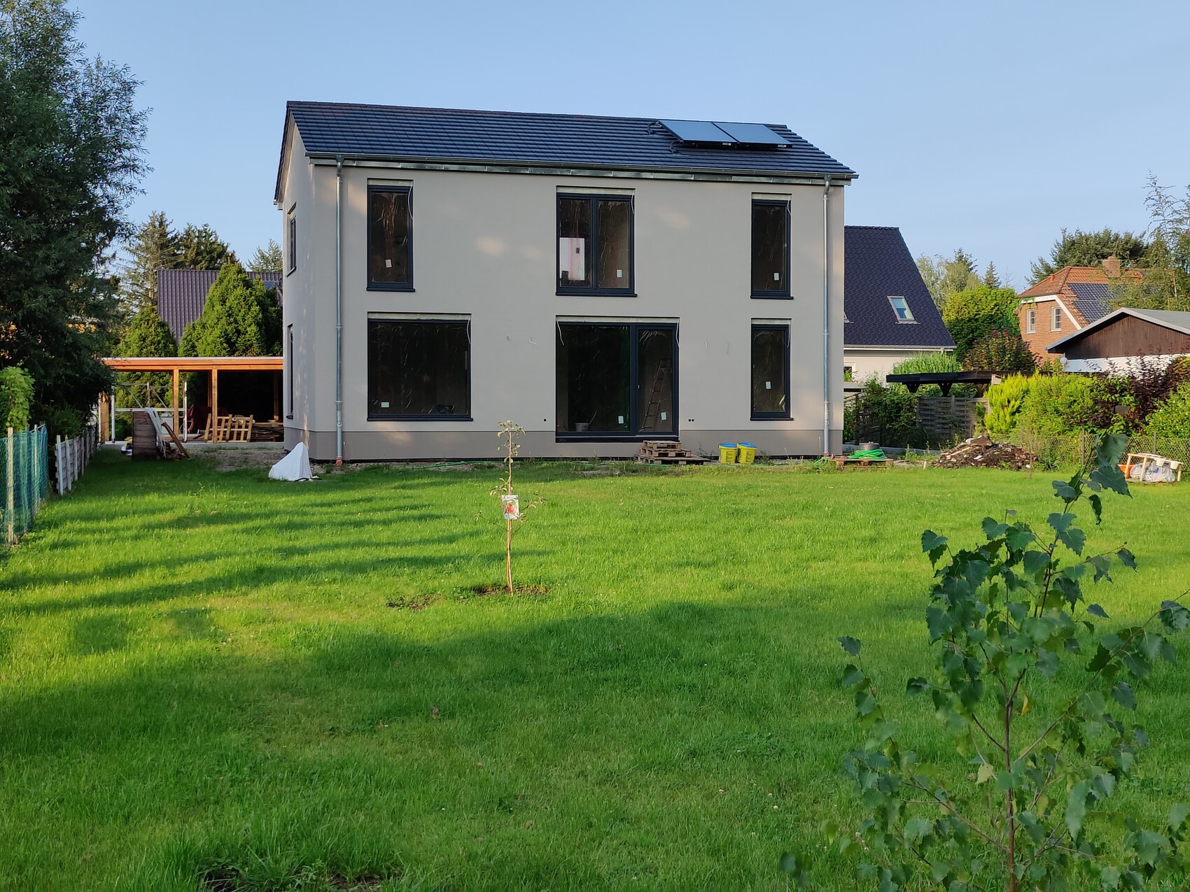 ZweistĂśckiges Haus im Bau mit grĂźnem Garten und Bauarbeiten