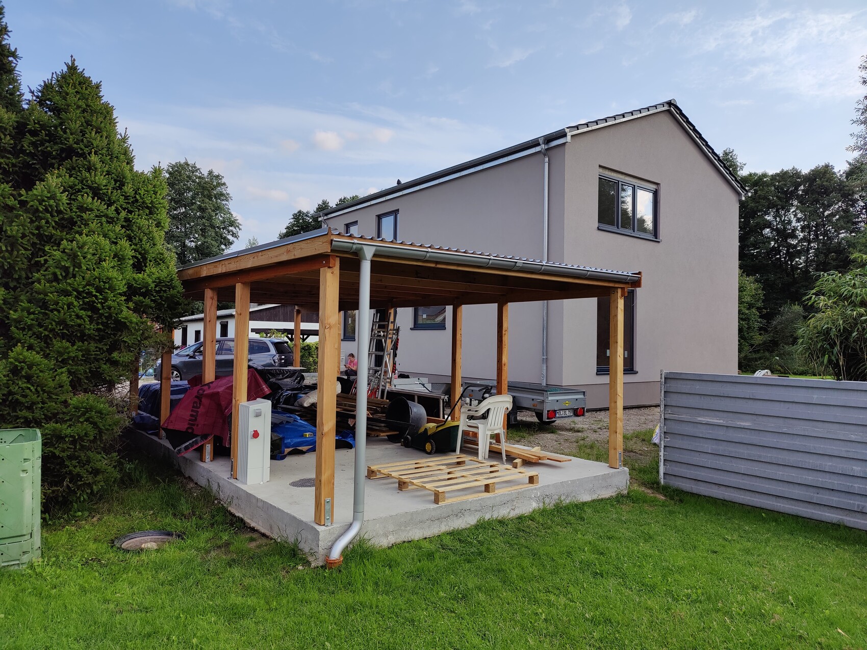 Modernes zweistĂśckiges Haus mit Holzcarport im Garten, Bauwerkzeuge sichtbar