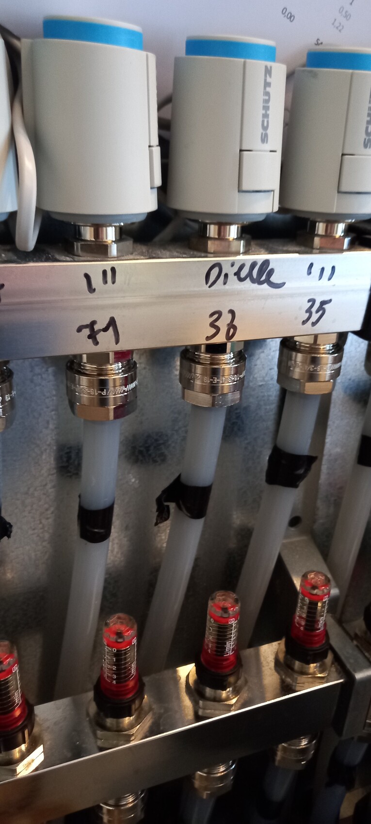 Close-up of valve block with hoses, metal fittings, and red scale indicators.