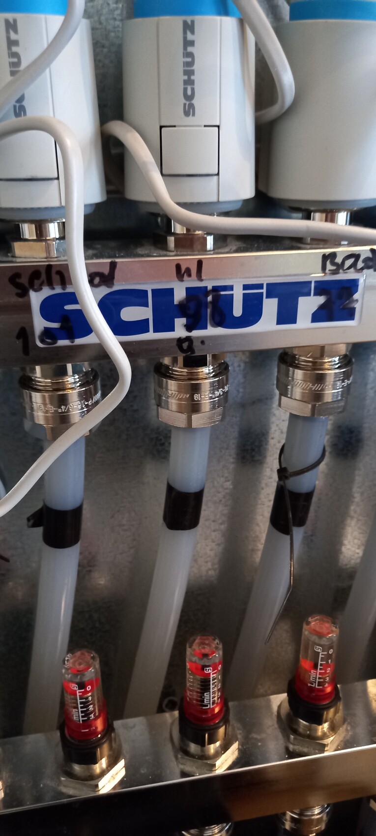 Close-up of pneumatic block with three hose connections and measurement gauges.