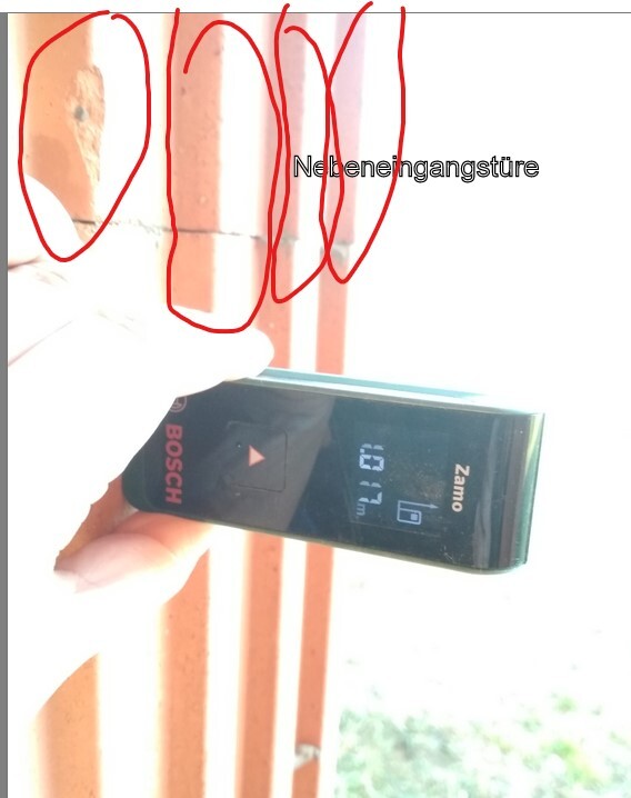 Hand hält Bosch-Laser-Entfernungsmesser vor roten Geländerpfosten; Display zeigt 0,7 m.