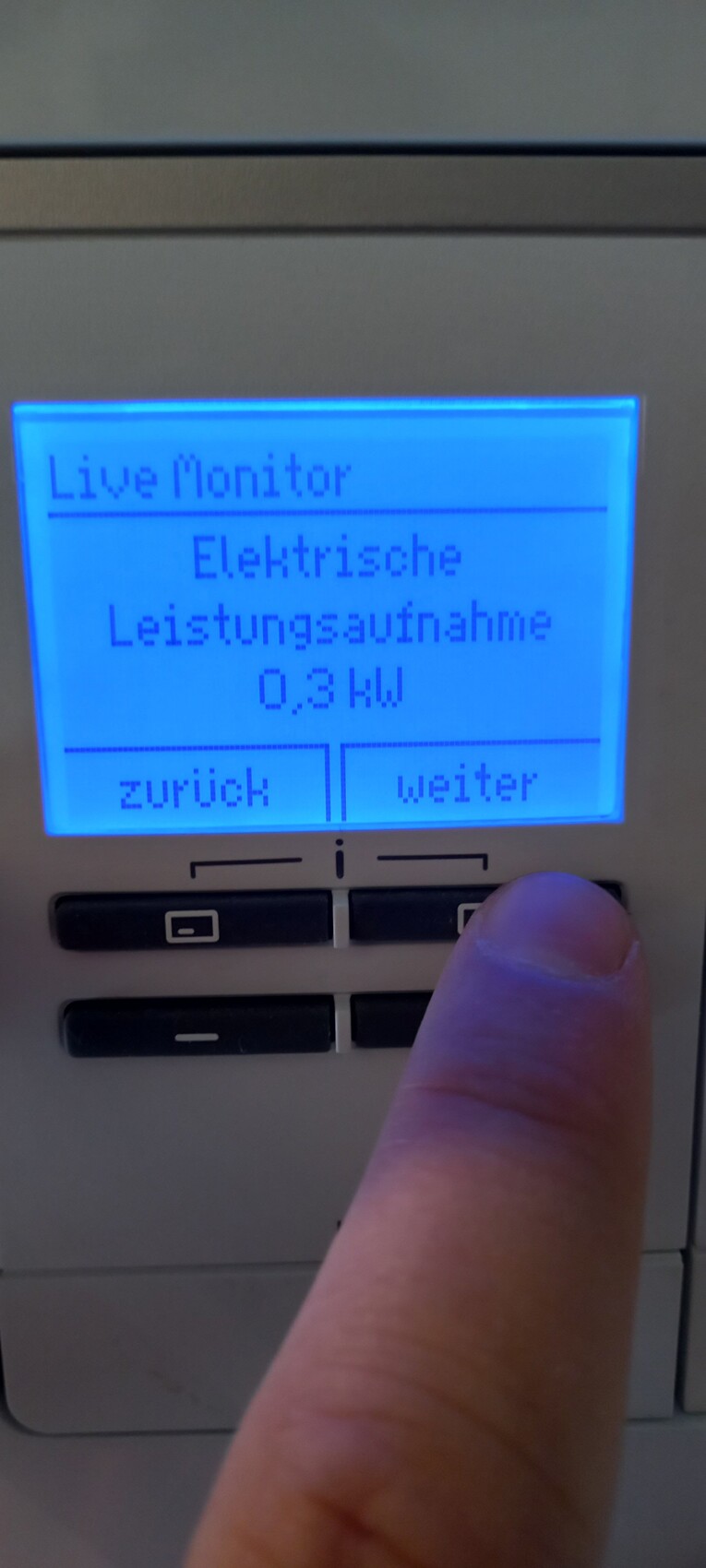 Blaues Display zeigt Live Monitor, 0,3 kW; Zurück/Weiter, Finger drückt.