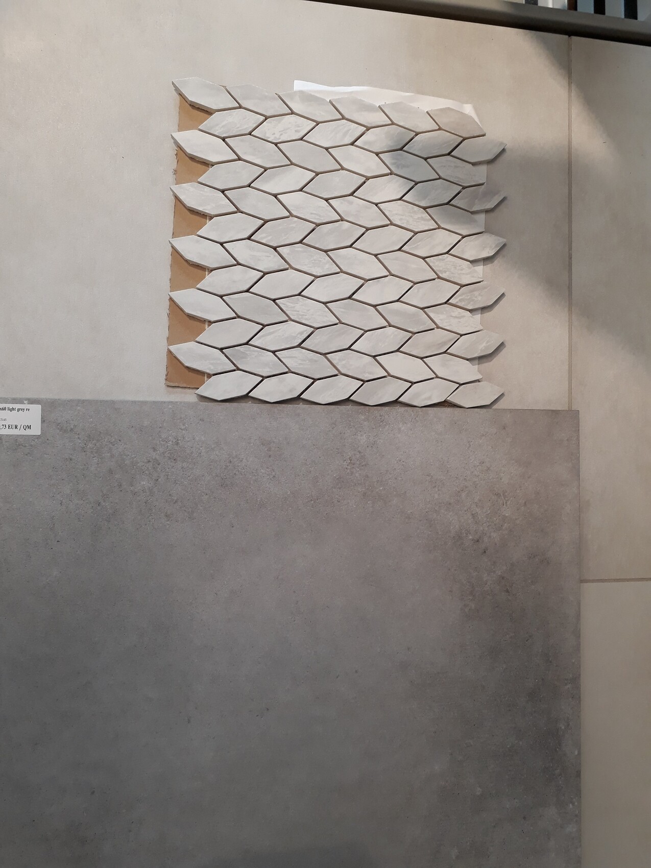 Wall panel with white honeycomb pattern made from hexagonal tiles above a grey tiled splashback.