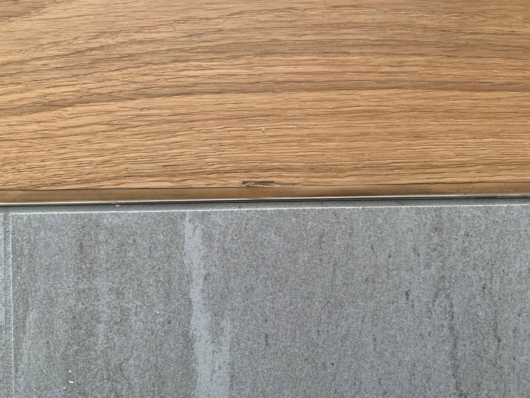 Transition from wooden floor above to grey floor below, metal edge at the border.
