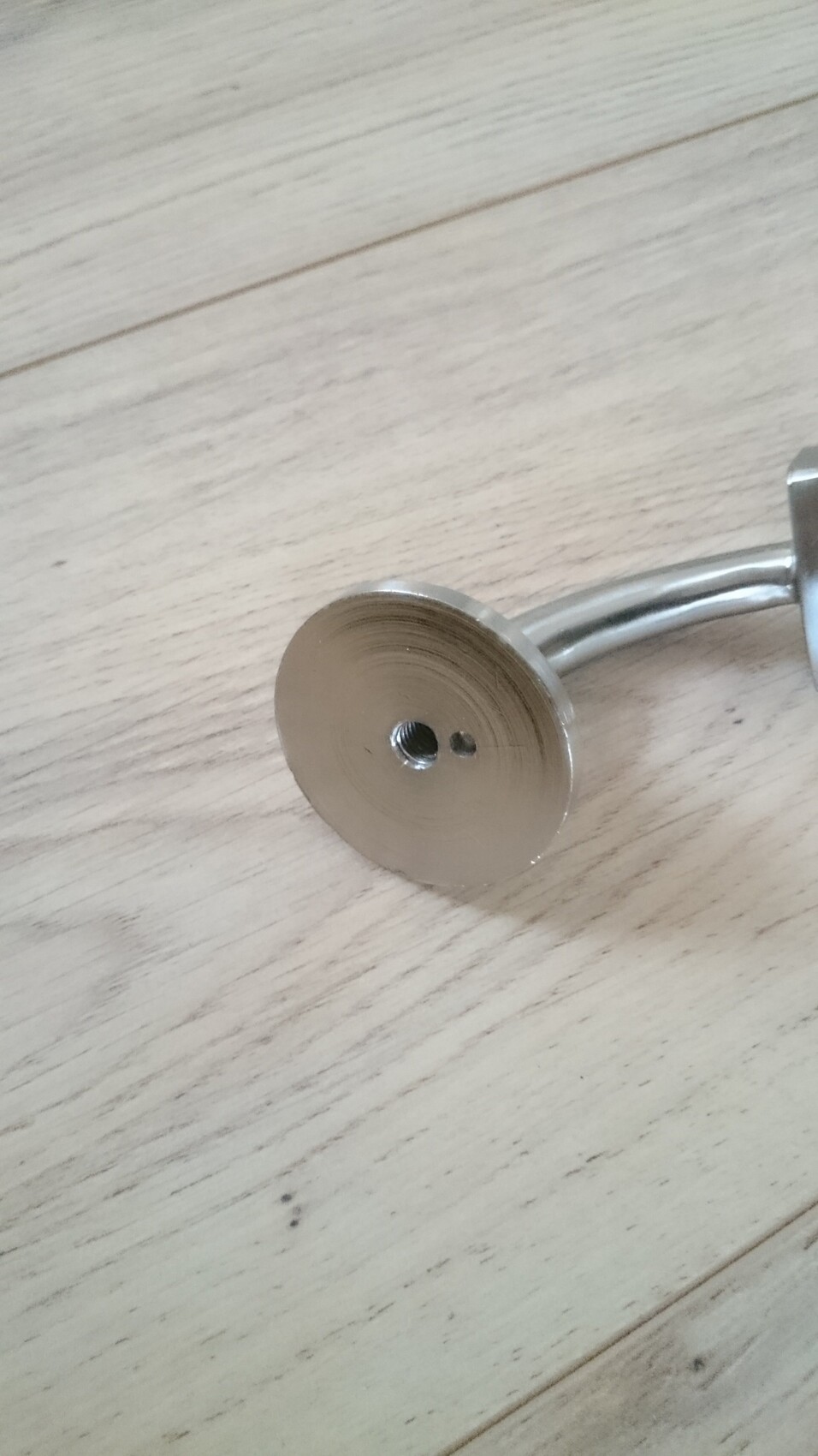 Runde Metallplatte mit Innengewinde auf hellem Holzboden